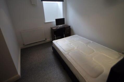 A compact single bedroom featuring a neatly mad...