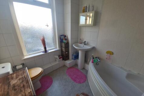 A bright and tidy bathroom featuring a bathtub,...