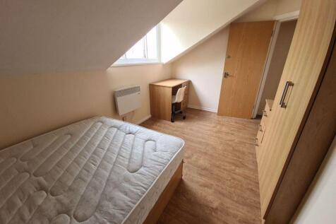 A cozy student bedroom featuring a double bed a...