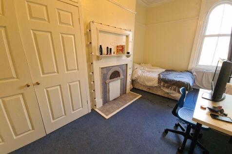 A cozy bedroom featuring a single bed, a window...