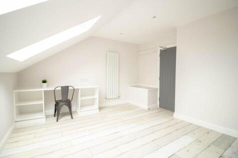 Bright, airy loft-style bedroom with sloped cei...