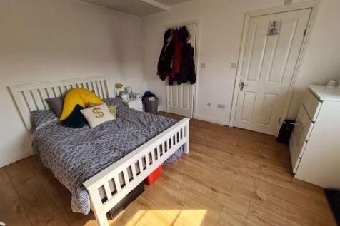 A bright and tidy bedroom featuring a white bed...