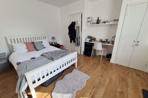 A bright and tidy bedroom featuring a cozy bed ...
