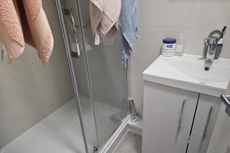 A modern bathroom featuring a glass-enclosed sh...