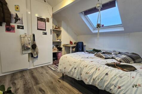 A cozy bedroom with a large bed, well-lit by a ...