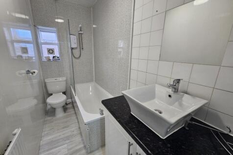 Modern shared bathroom with a white bathtub and...