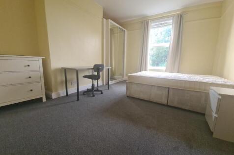A well-lit bedroom featuring a single bed, a dr...