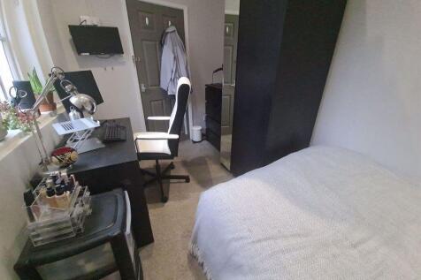 A cozy bedroom featuring a neatly made bed, wit...