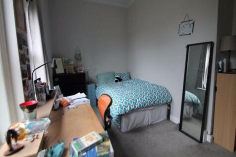 A cozy student bedroom featuring a bed with pat...