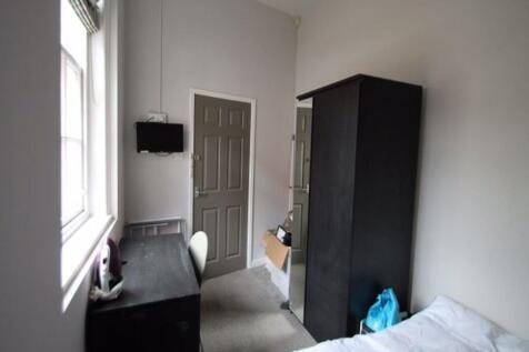 A tidy and well-lit student bedroom featuring a...