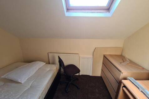 A cozy single bedroom featuring a bed, a small ...