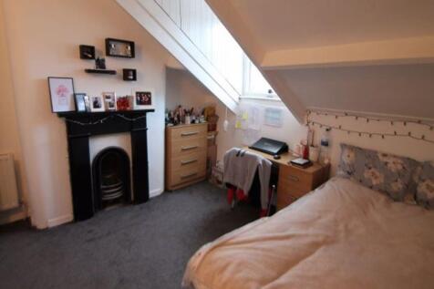 A cozy bedroom with a sloped ceiling, featuring...