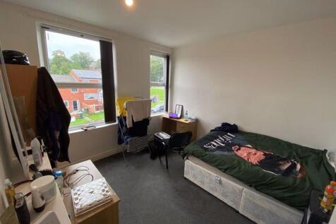 A cozy single bedroom featuring a bed with a co...