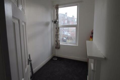 A small, simply furnished bedroom with a window...