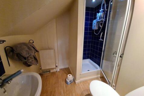 A compact bathroom featuring a corner shower wi...