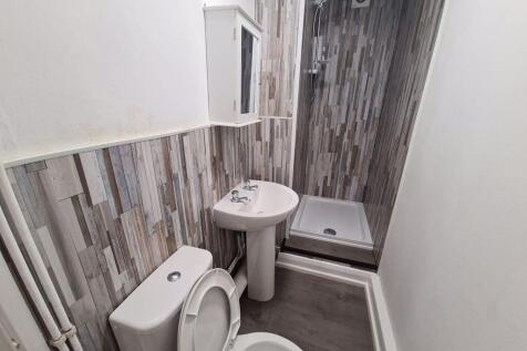 A clean, modern bathroom with a toilet, sink, a...