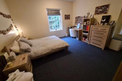 A spacious double bedroom featuring a large bed...