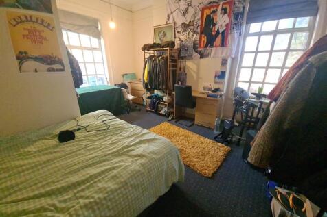 A cozy bedroom featuring a neatly made bed, two...