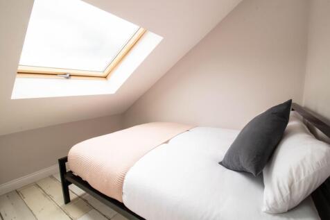 A bright and cozy single bedroom featuring a si...