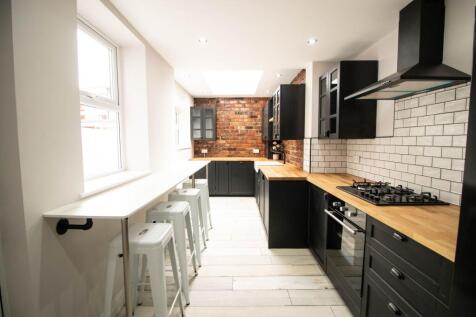 Modern kitchen with black cabinetry, wooden cou...