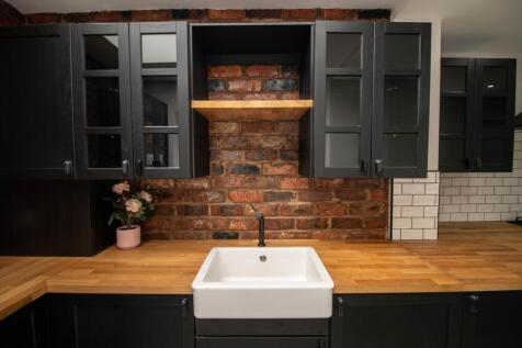 A modern kitchen featuring a rustic brick backs...
