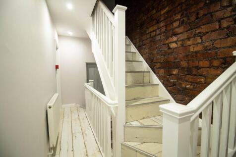 Bright painted hallway with white wooden stairs...