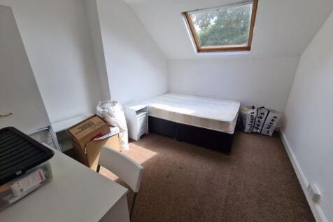 A compact single bedroom with a sloped ceiling,...