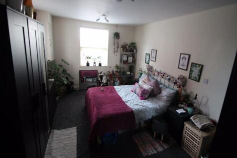 A well-lit, tidy bedroom featuring a comfortabl...