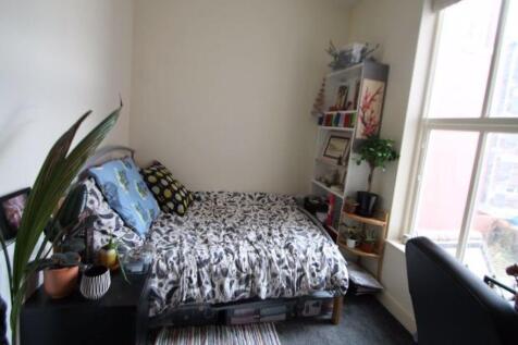 A cozy single bedroom featuring a bed with a pa...