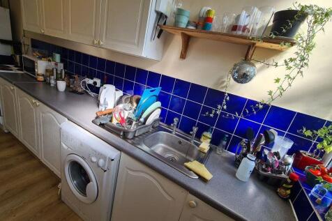 A well-equipped kitchen with a blue tiled backs...