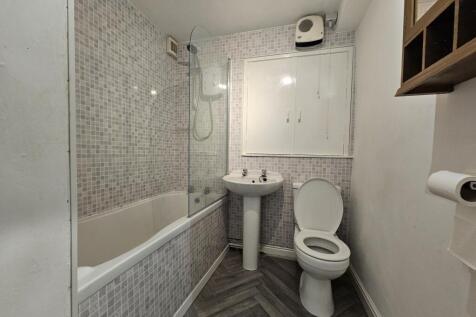 A modern bathroom featuring a bathtub with a gl...