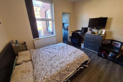 A warmly lit bedroom featuring a comfortable do...