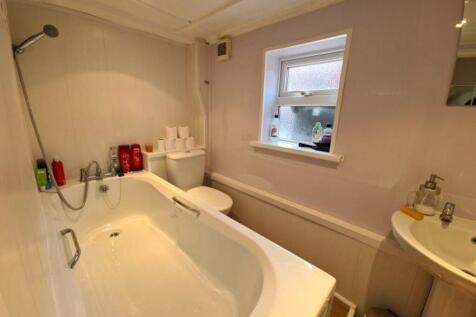 Bright and clean bathroom suite featuring a lar...