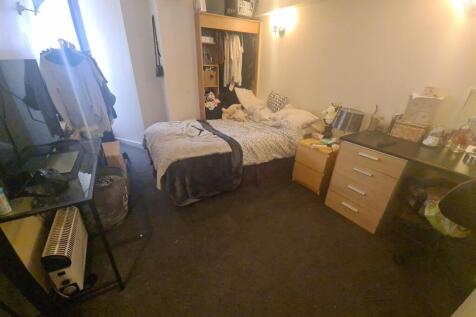 A cozy single bedroom featuring a bed, a desk, ...