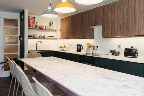 A modern, well-lit kitchen featuring a long mar...
