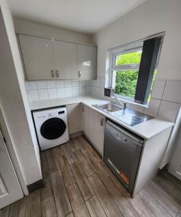 A bright and modern kitchen featuring white cab...