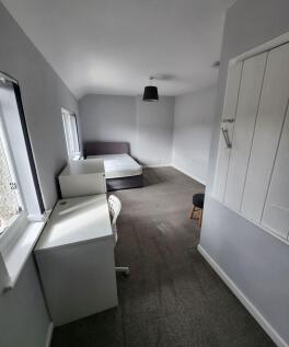 A bright and simple bedroom featuring two windo...