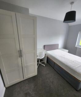 A bright, tidy bedroom featuring a comfortable ...