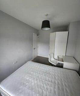 A tidy, well-lit bedroom featuring a simple whi...