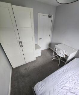 A neat and bright small bedroom featuring a whi...
