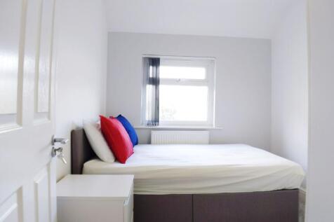 Bright, neutrally decorated bedroom with a comf...