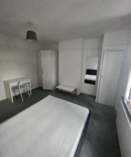 A minimalist bedroom with a clean, white bed an...