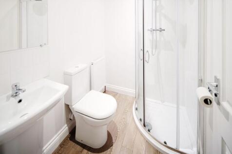 Bright, modern bathroom with a curved glass sho...