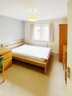 Bright, neutral double bedroom with a wooden be...