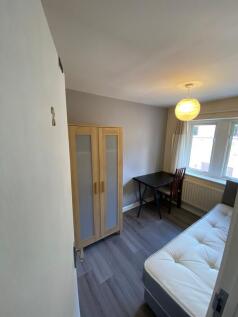 A modest student room featuring a bed, a small ...