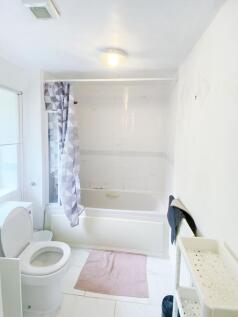 Bright, clean bathroom with a full bathtub and ...