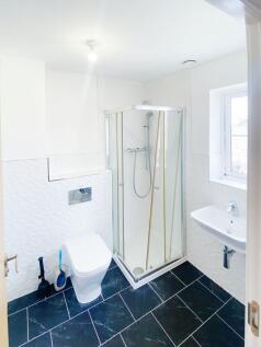 Bright modern bathroom with a corner glass show...