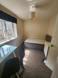 A modest student bedroom featuring a single bed...