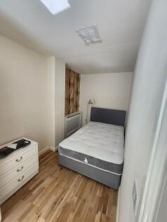 A cozy single bedroom featuring a large bed wit...