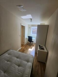 A cozy bedroom featuring a single bed, a small ...